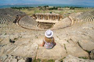 a girl in a hat sits in a roman amphitheater in th 2022 02 07 09 12 42 utc