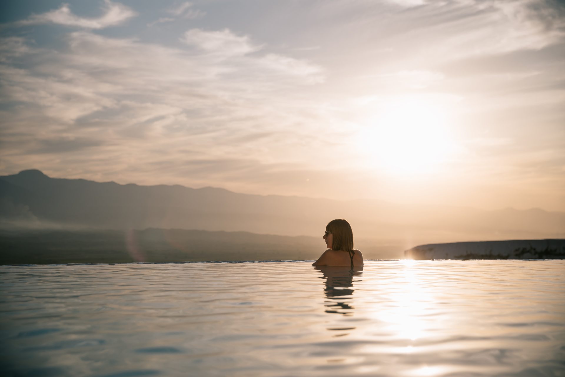 young woman relaxing in beautiful pool at sunset 2022 12 16 19 17 32 utc